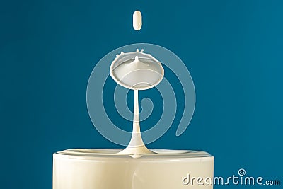 Two drops of milk fall into the long drink glass hitting each other then the liquid surface is shaped like a mushroom Stock Photo