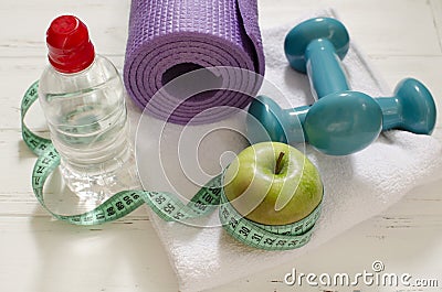 Two dumbbells, bottle of water, green apple, centimeter on white Stock Photo