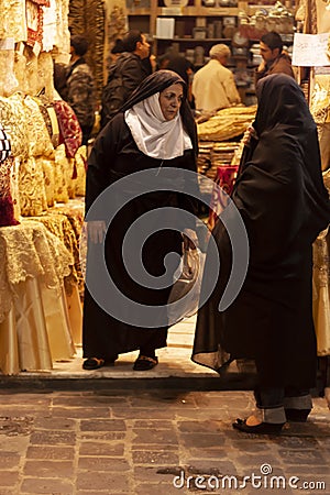 Two elderly Syrian women wearing black hijab are standing in front of a boutique shop Editorial Stock Photo