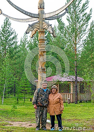 Two elderly Yakuts a man and a woman stand hugging and smiling under the national ritual pillar of Serge Stock Photo