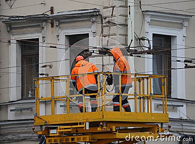 Two electrical workers in orange uniforms at work Editorial Stock Photo