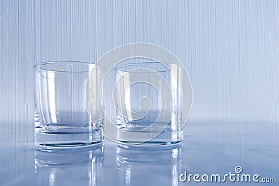 Two empty glasses on a light background.Glass cups for drinks,standing on a white table.Composition of two glasses for water . Stock Photo