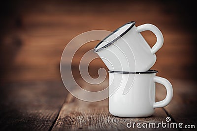 Two enameled cups on wooden rustic kitchen table. Stock Photo