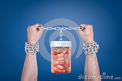 Two enchained male hands holding up a pills jar which is hanging on the same chain. Stock Photo