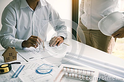 Two engineering working together and using compass looking blueprint and analysis with architectural plan on desk Stock Photo