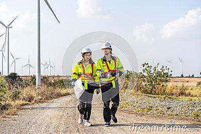 Two engineers caucasian man and woman in hardhat and goggles talk about system installation and walking to verify that a wind Stock Photo