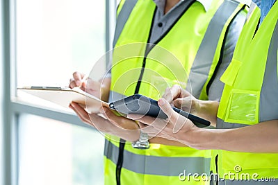 Two engineers man standing in front of windows and used tablet to find construction model Stock Photo