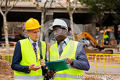 Two engineers talking about road repairing works documentation Stock Photo