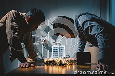 Two Engineers testing efficiency of solar cell panels type with Led light in office at night. Learn design and calculation to Stock Photo