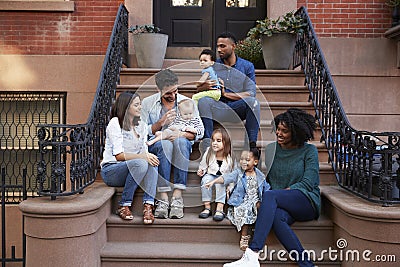 Two families with kids sitting on front stoops Stock Photo