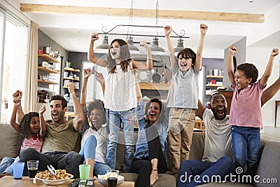 Two Families Watching Sports On Television And Cheering Stock Photo