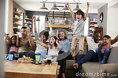 Two Families Watching Sports On Television And Cheering Stock Photo