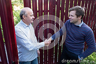two farmers shaking hands and takling to each other on sunny day Stock Photo