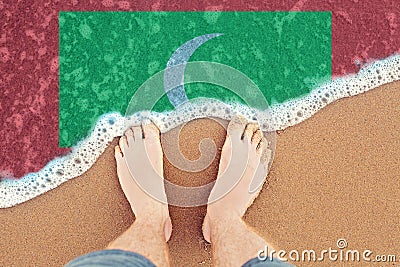 Two Feet on sandy beach with flag Maldives. Top View on sea surf Stock Photo