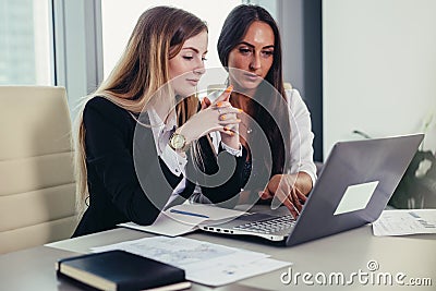 Two female accountants working together on financial report using laptop sitting at desk in account department Stock Photo