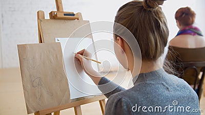 Two female artists sketching model in bright drawing class Stock Photo