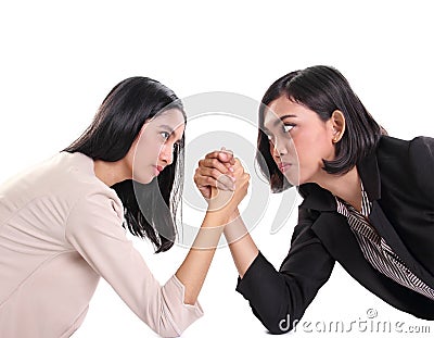 Two female business workers face each other in arm wrestling battle, white background Stock Photo