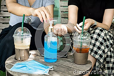 Two female customers cleaning their hand with alcohol gel at coffee shop, new normal concept Stock Photo