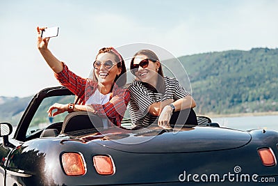 Two female freinds take a selfie photo in cabriolrt car during t Stock Photo
