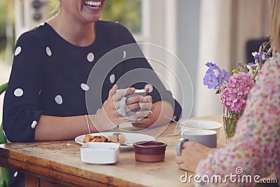 Two Female Friends In Coffee Shop Meeting Up In Socially Distanced Way Viewed Through Window Stock Photo