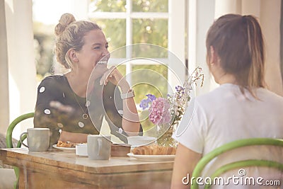 Two Female Friends In Coffee Shop Meeting Up In Socially Distanced Way Viewed Through Window Stock Photo