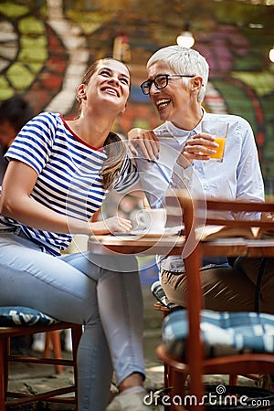 Two female friends of different generations joking while they have a drink in the bar. Leisure, bar, friendship, outdoor Stock Photo