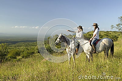 Two female horseback riders on horseback ride at sunset overlooking Lewa Wildlife Conservancy in North Kenya, Africa Editorial Stock Photo