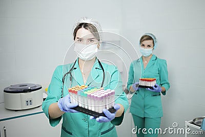 Two female nurse doctor in a medical mask hold test tubes for a blood test Stock Photo