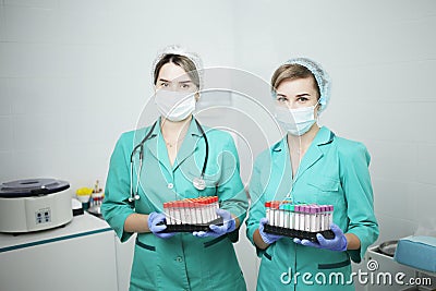 Two female nurse doctor in a medical mask hold test tubes for a blood test Stock Photo