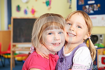 Two Female Pre School Pupils Hugging One Another Stock Photo