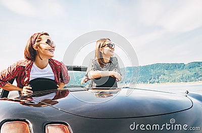 Two females friends traveling by cabriolet, have a stop brake to enjoy a mountain landsxapes Stock Photo