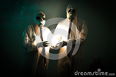 Two figures wearing biohazard suits hold a strange light Stock Photo