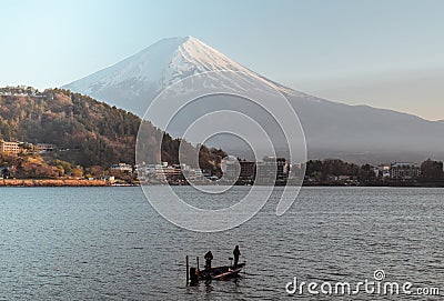 Two fishermen fishing on a boat at Lake Kawaguchi with Mount Fuji Stock Photo