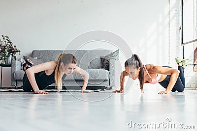 Two fitness women warming up doing push-ups exercise working out at home Stock Photo