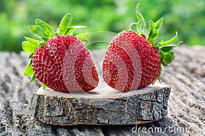 Two fresh appetizing strawberries on a wooden table in the garden Stock Photo