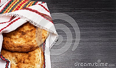 Two fresh pita bread covered with festive napkin on wooden table Stock Photo