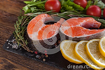 Two fresh salmon steakes with greenery, lemon and cherry tomatoes Stock Photo