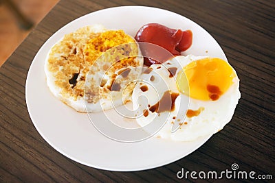 Two fried eggs with tomato sauce and soy sauce in white plate on Stock Photo