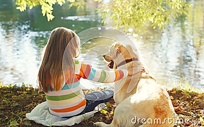 Two friends, child with Labrador retriever dog sitting in summer Stock Photo