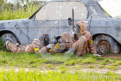 Two friends defend old car in paintball mission Stock Photo