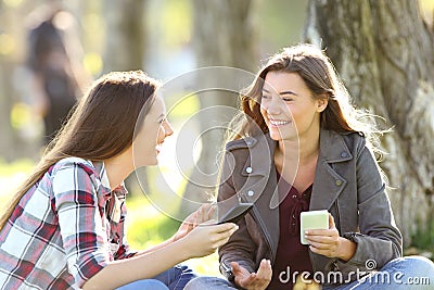 Two friends talking holding their smart phones Stock Photo