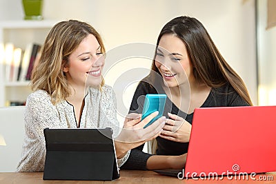 Two friends using multiple devices at home Stock Photo