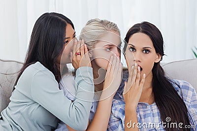 Two friends whispering secret to shocked brunette Stock Photo