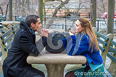 Two friends, young man and young woman, sitting outdoors in winter, talking Stock Photo