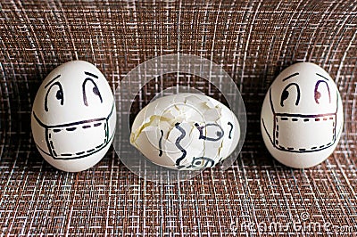 Two frightened eggs in medical masks look at a cracked egg. Stock Photo