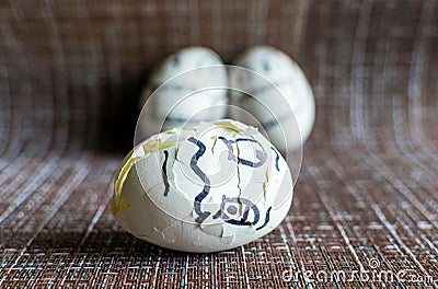 Two frightened eggs in medical masks look at a cracked egg. Stock Photo