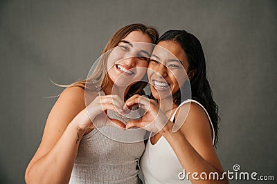 Two fun-loving girlfriends making a heart sign with there hands Stock Photo