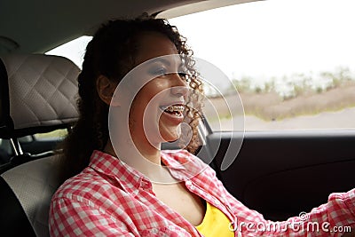 Two fun young women in sunglasses driving in a car in town laughing and smiling as they socialise together, view through Stock Photo