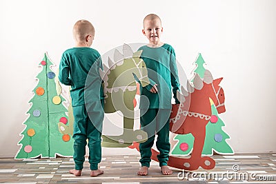 Two funny boys in a Santa Claus hat are playing with horses drawn on cardboard. The guys have fun at home. Christmas holiday conce Stock Photo