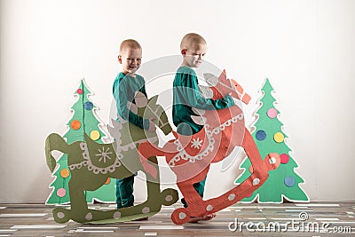 Two funny boys in a Santa Claus hat are playing with horses drawn on cardboard. The guys have fun at home. Christmas holiday conce Stock Photo